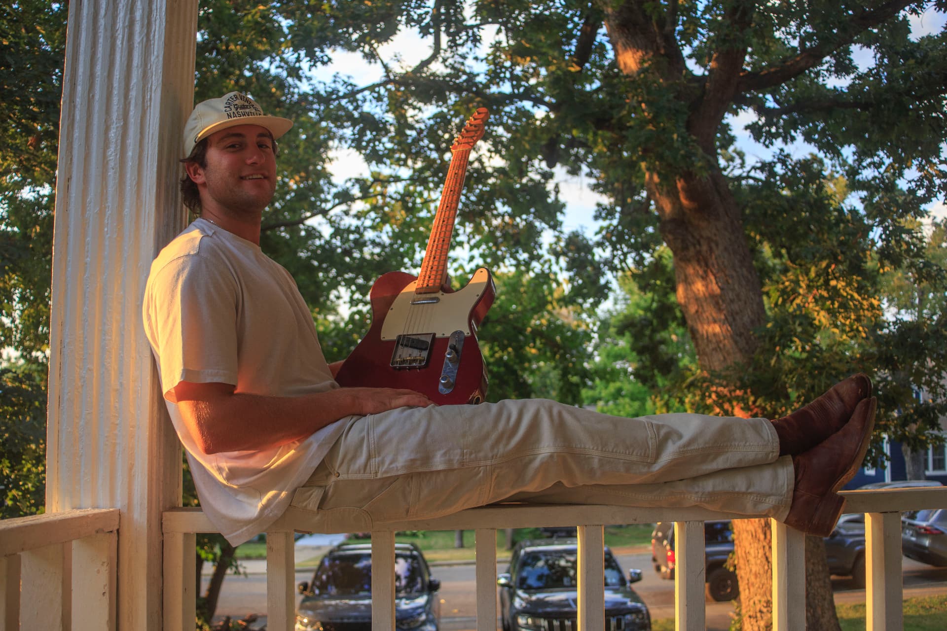 Dante DeRosa with his guitar on a porch at golden hour