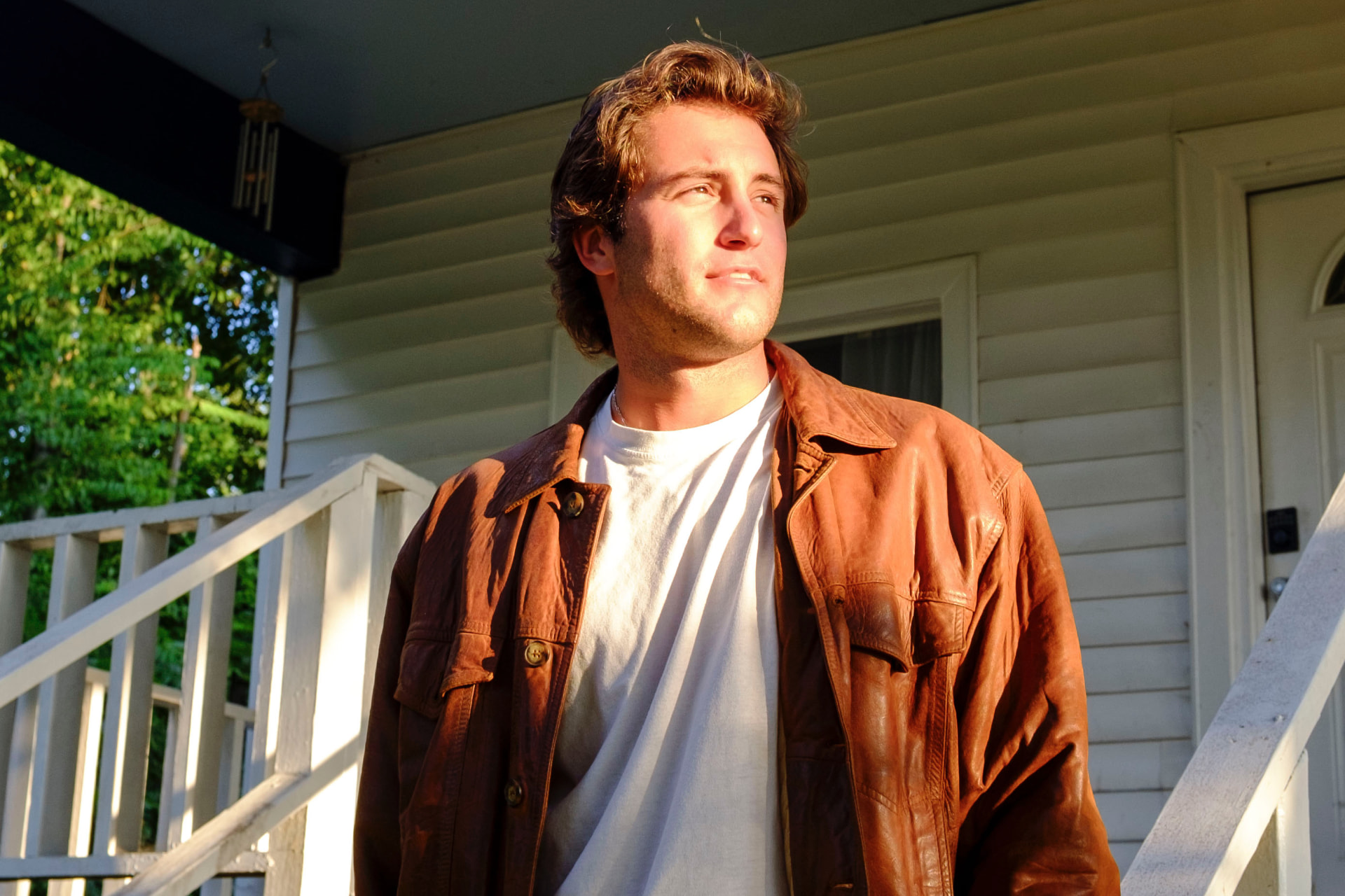 Dante DeRosa in a leather jacket looking out from the porch in warm evening light